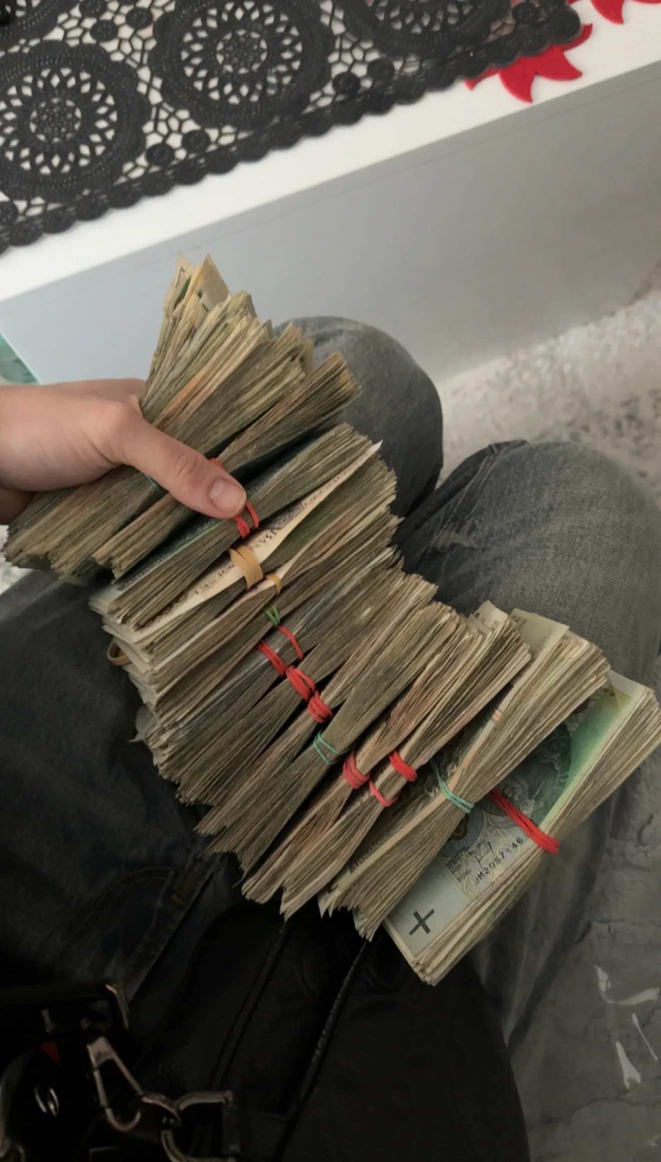 Pliki banknotów spięte gumkami trzymane w dłoni