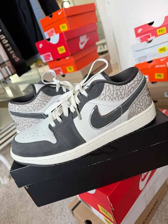 Szaro-białe buty Air Jordan 1 Low na pudełku, w tle kartony Nike